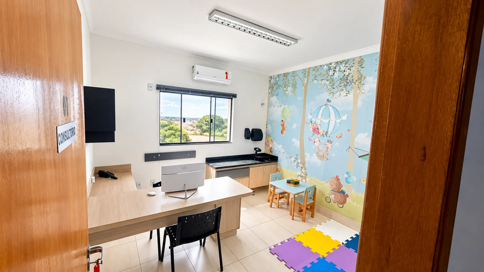 Consultório com mesa de atendimento e mural infantil de balão e animais