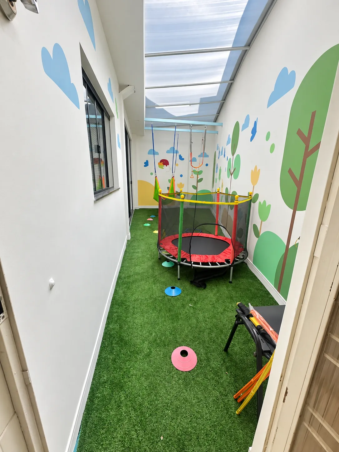 Espaço de movimento com cama elástica, balanços e piso de grama sintética