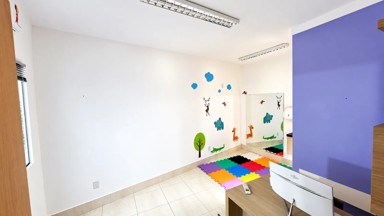 Sala de terapia com espelho, adesivos de animais e tapete de EVA